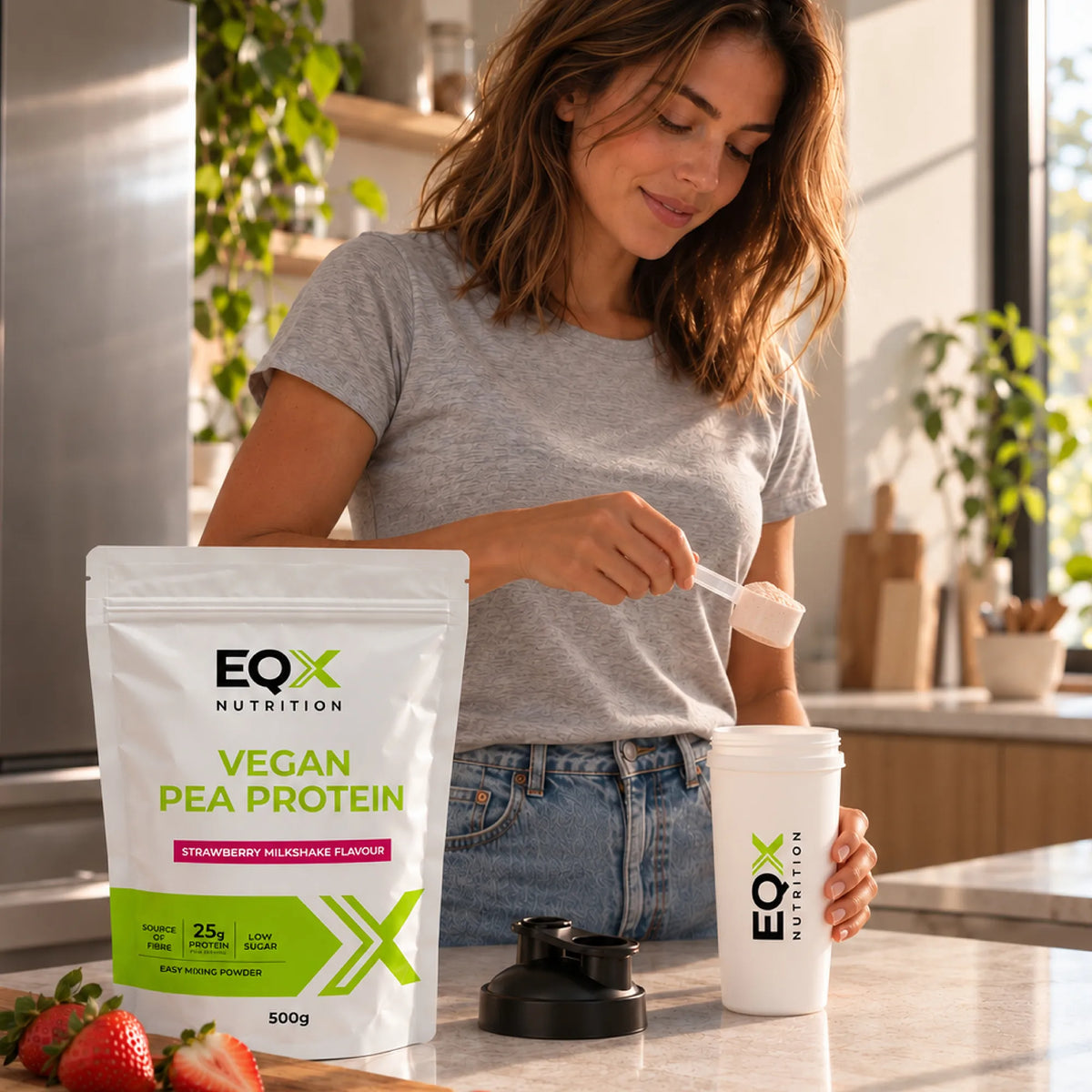 Woman preparing an EQX Vegan Pea Protein Strawberry Milkshake protein shake in the kitchen.